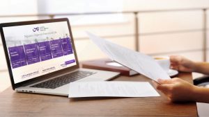 Laptop mostrando documento CMF de regulación financiera con papeles de póliza de seguro sobre mesa de trabajo